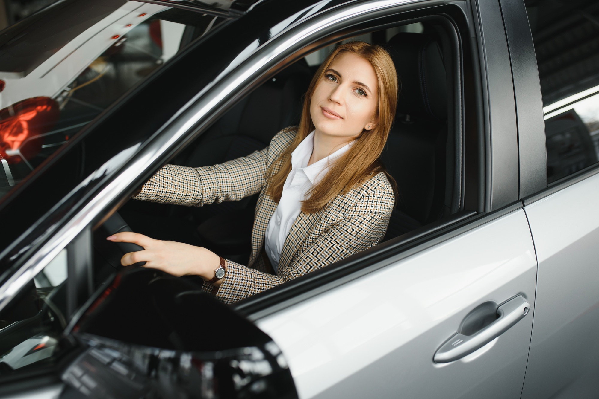 Photo of happy young woman sitting inside her new car. Concept for car rental.